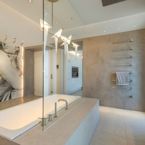 Luxuriöses Badezimmer mit freistehender Wanne, fugenloser Wandgestaltung in warmer Betonoptik und modernem Handtuchheizkörper – elegantes Spa-Feeling mit mineralischer Oberfläche