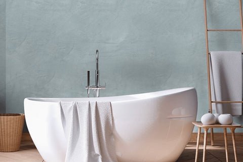 Verputzte Wand in Meeresdunst mit freistehender Badewanne – atmungsaktiver Mineralputz für Wohnräume.