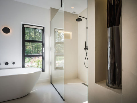 Modernes fugenloses Bad in warmer Betonoptik und freistehender Badewanne