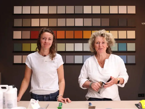 Die Malermeister Fee und Ursel vor einer Wand mit Farbmustern bei der Beratung für die Erstellung einer fugenlosen Dusche.