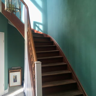 Eine sehr schöne alte dunkle Holztreppe, die in dem türkisgrün gestrichenen Treppenhaus sehr edel wirkt.