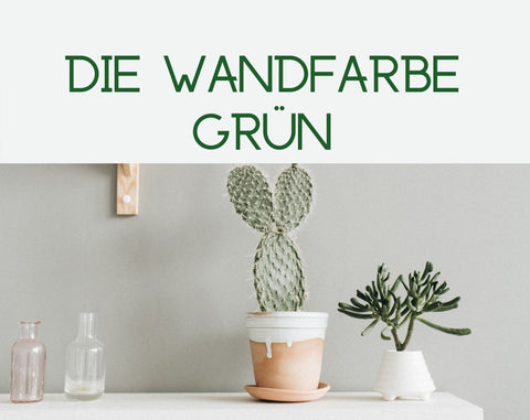 Stilleben mit Kaktus und Vasen vor einer grün-grauen Wand.