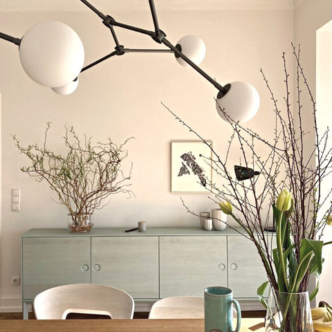 „Heller Wohn- und Essbereich mit wohngesunder, matter Wandfarbe in warmem Naturton – kombiniert mit modernem Design, minimalistischer Pendelleuchte und Sideboard in Salbeigrün