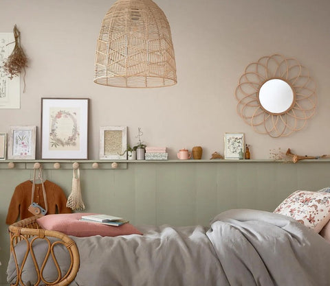 Liebevoll eingerichtetes Kinderzimmer mit halbhoch gestrichener Wand in natürlichem Salbeigrün und wohngesunder Wandfarbe – kombiniert mit Rattanmöbeln, Trockenblumen und sanften Naturtönen für ein gesundes Wohnklima