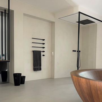 Sehr modernes Badezimmer mit offener Dusche und einer Holzbadewanne, dessen Wände mit ein hellen Beton Cire fugenlos verputzt sind.
