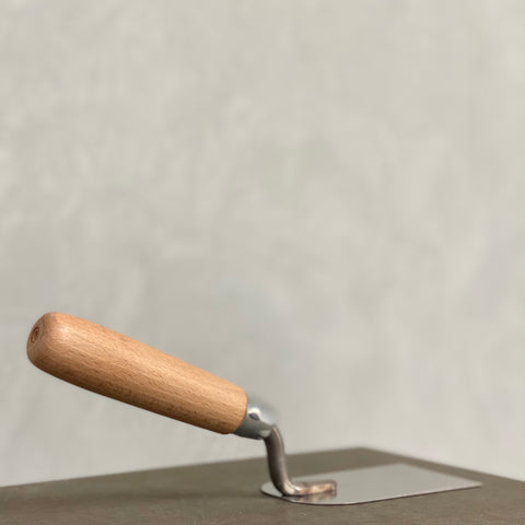 Stuckateurkelle mit Holzgriff zum Auftragen und Verarbeiten von Mineralputz auf Wandflächen.